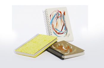 Foto com três cadernetas com capas artesanais