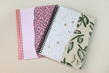 Foto com dois cadernos com capas artesanais feitas com colagens e papel reciclado